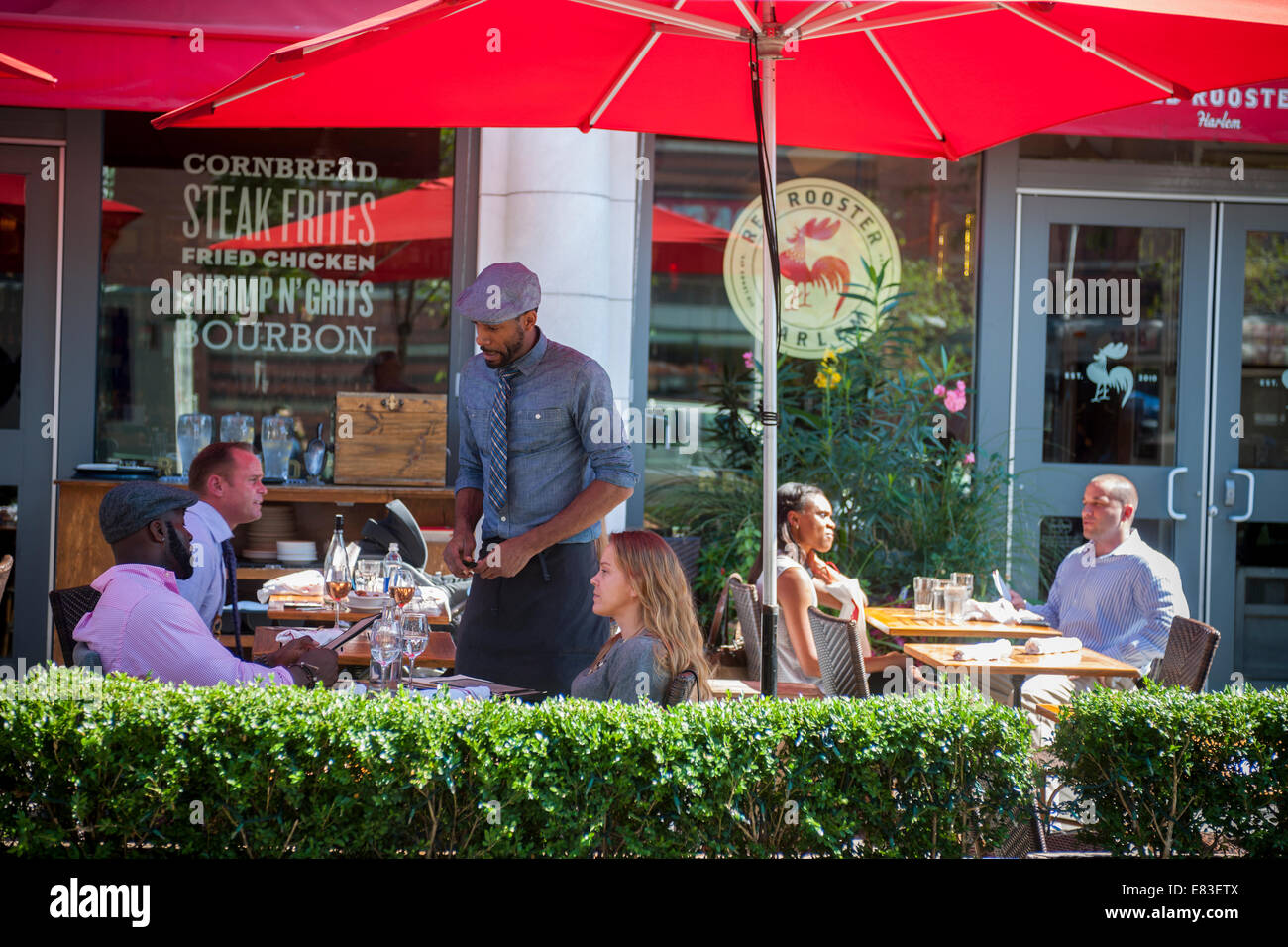 Patrons are served at the outdoor cafe of the Red Rooster restaurant on Lenox Avenue in the