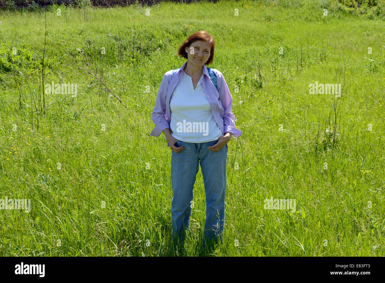 Full length portrait of mature woman in jeans and shirt on bright green ...
