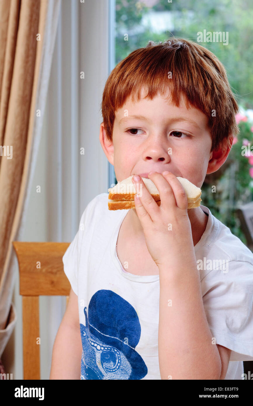 A young boy taking a bite out of a sandwich Stock Photo