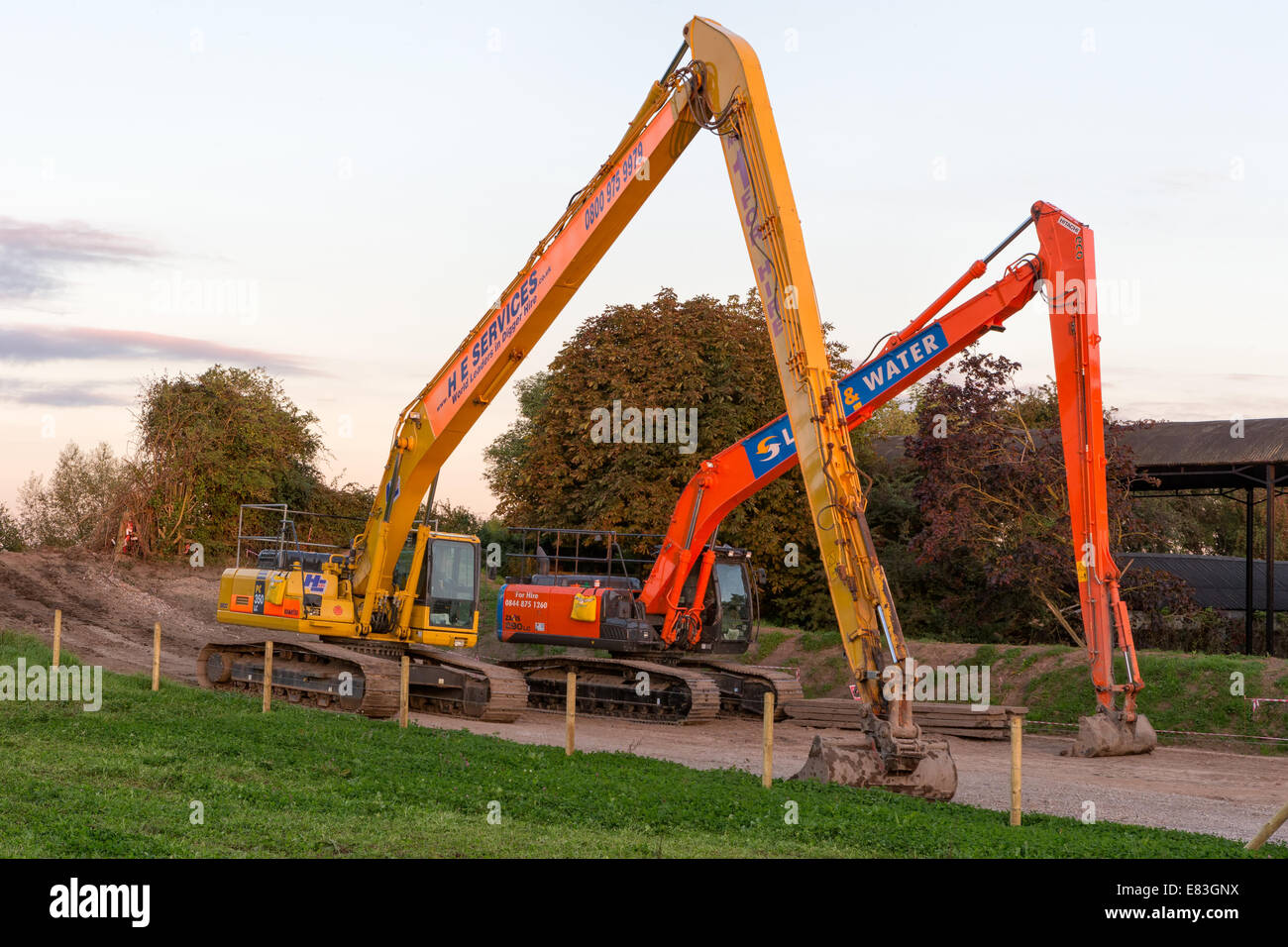 Long-reach excavators parked up at the end of another busy day dredging the main channel of the River Parrett at Burrowbridge Stock Photo