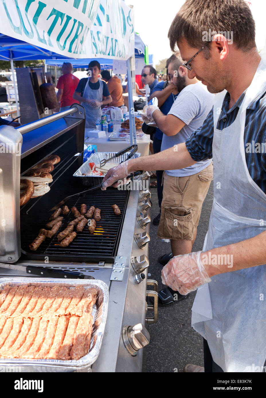 Man cooking Turkish cevapi on grill at outdoor festival - USA Stock Photo
