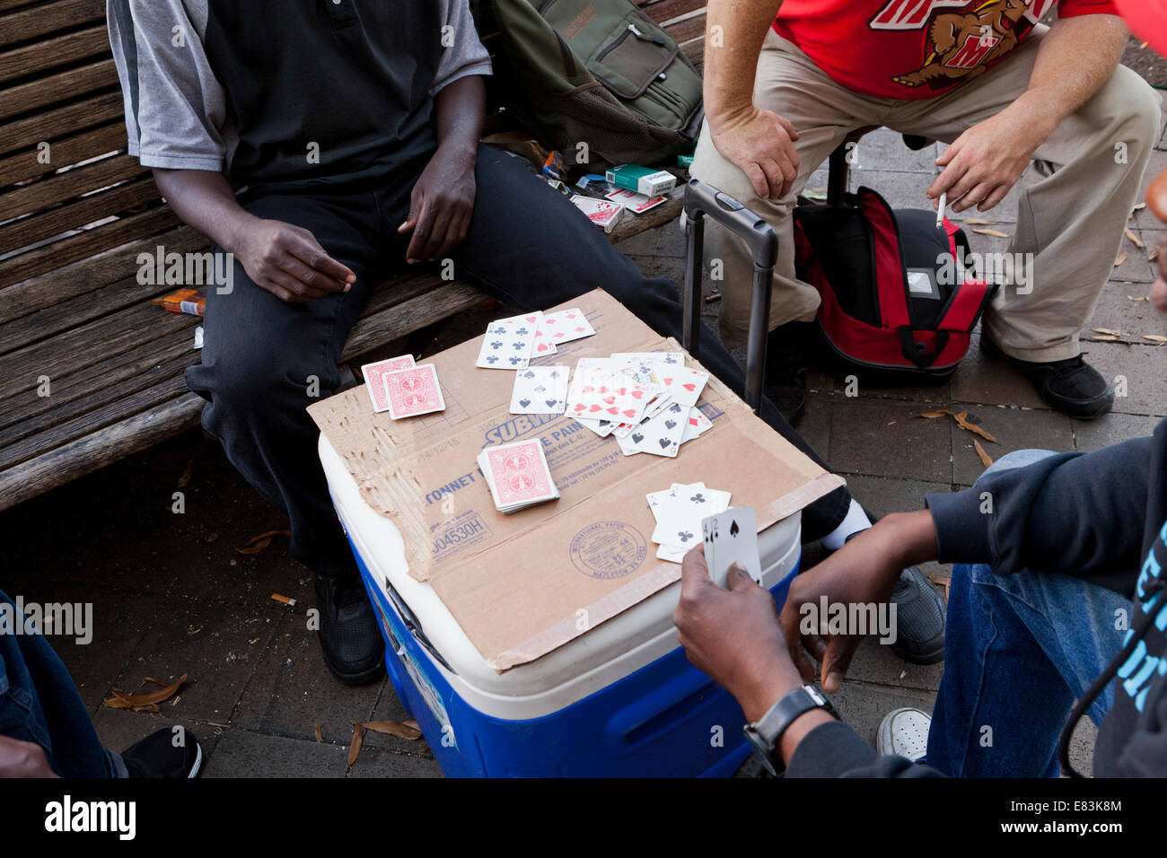 Men playing cards in public park bench - USA Stock Photo