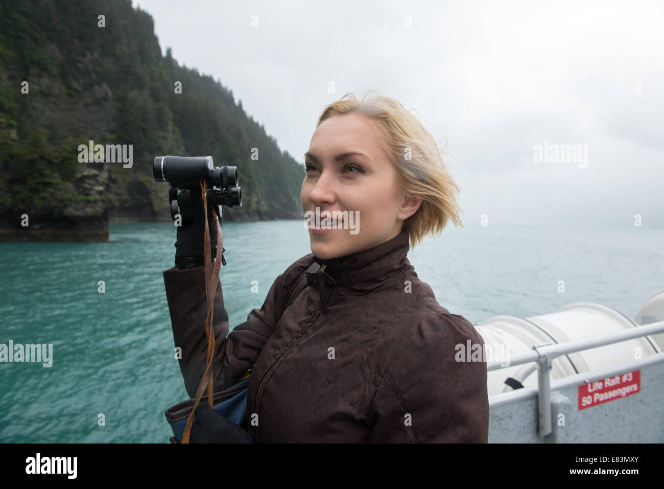 Woman using binoculars to spot wildlife on cruise of Resurrection Bay Alaska Stock Photo