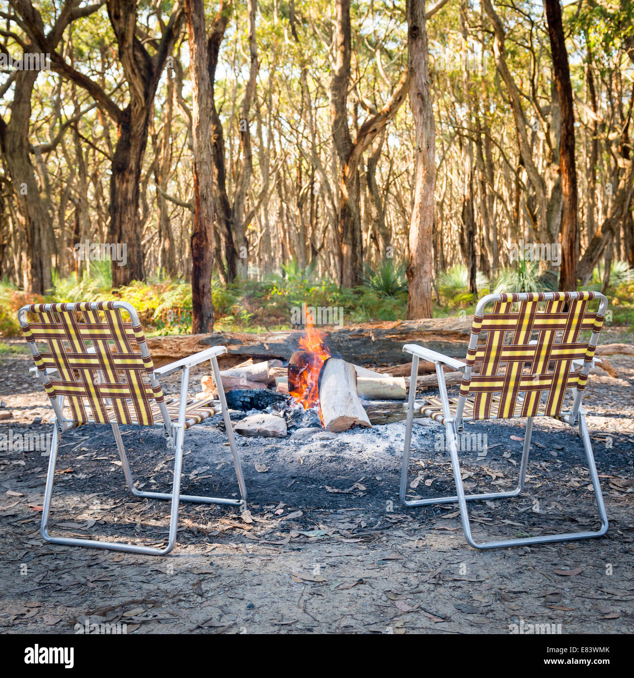 Retro foldup chairs sitting around the campfire in the woods Stock