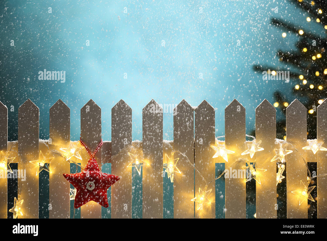 Red fabric star and lights hanging on fence at snowy night,Christmas concept. Stock Photo