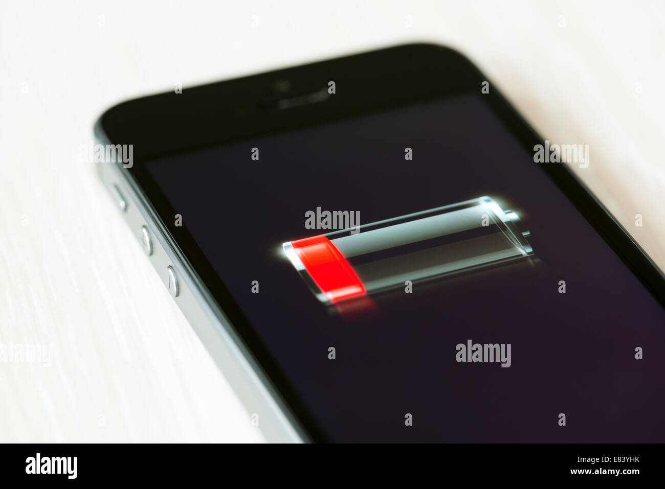 The brand new Apple iPhone 5S lying on a desk with low battery symbol on a screen Stock Photo