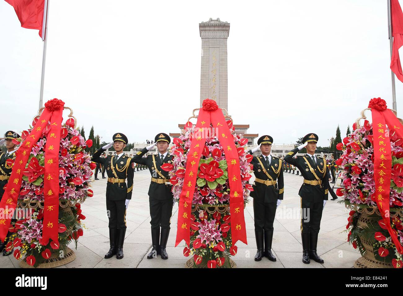 Beijing, China. 30th Sep, 2014. Soldiers salute as presenting flower baskets to honor and remember the deceased national heroes at the Monument to the People's Heroes in Tian'anmen Square, downtown Beijing, capital of China, Sept. 30, 2014, on the occasion of the first Martyrs' Day. Credit:  Lan Hongguang/Xinhua/Alamy Live News Stock Photo