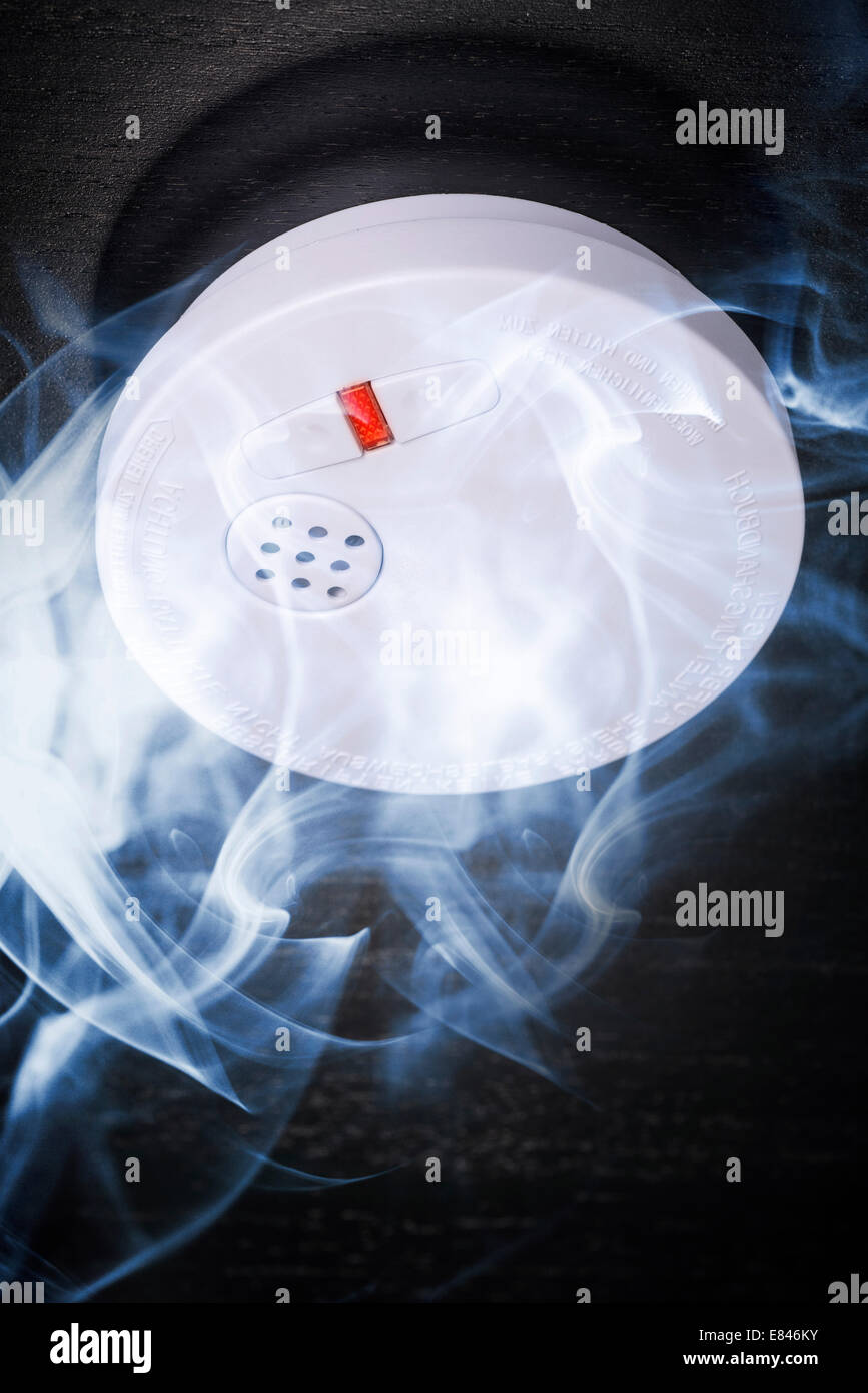 Smoke detector in the smoke of a fire. Stock Photo