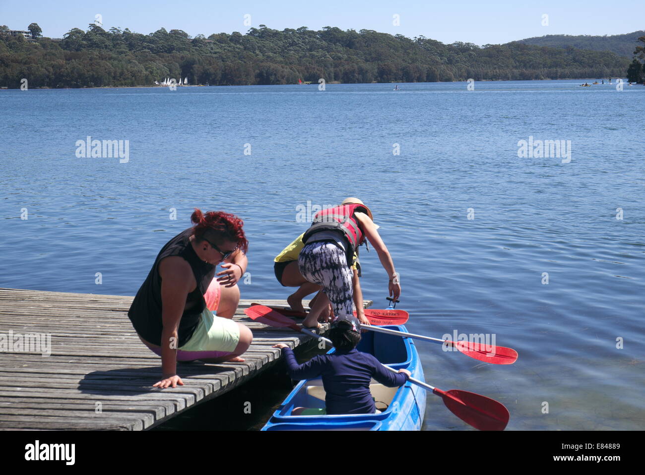 father and children get ready for a canoe kayak paddle on narrabeen