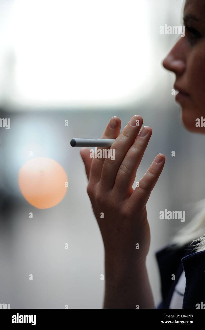 A girl holds a e-cigarette in her hand. Stock Photo