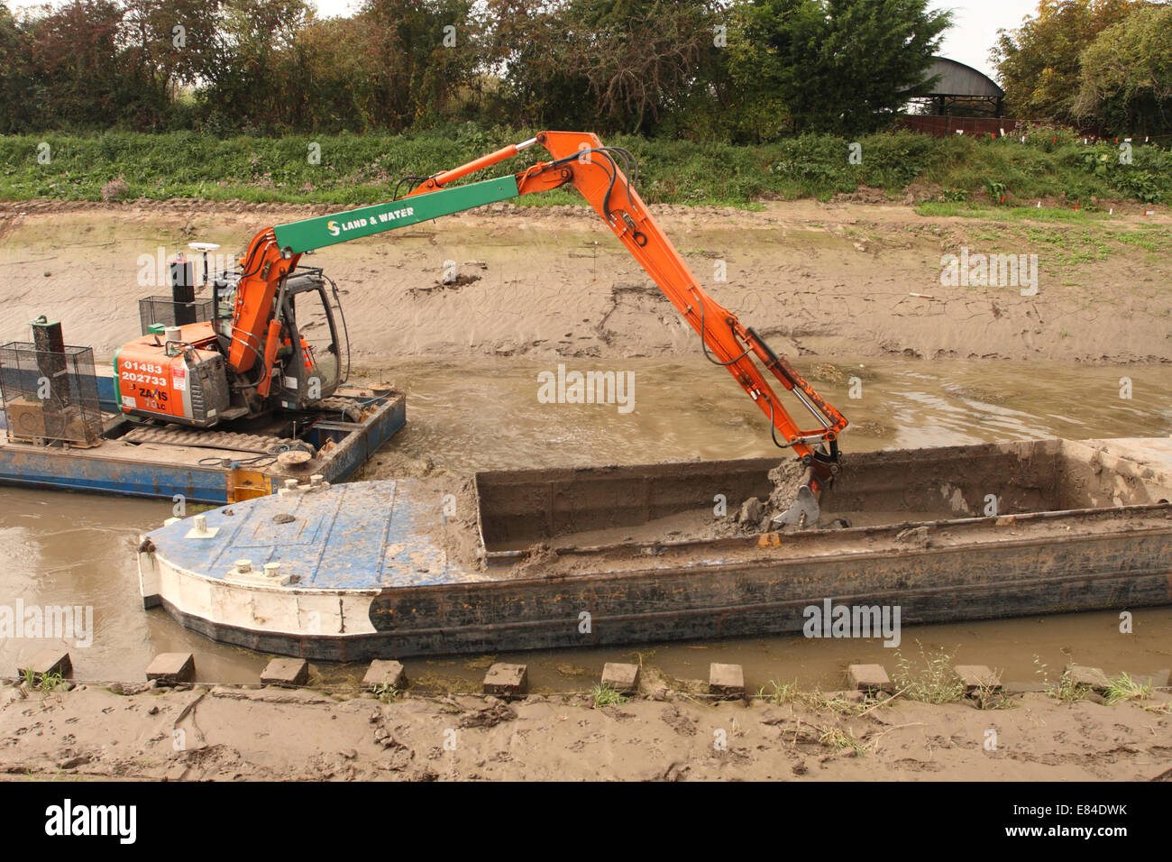 Burrowbridge, Somerset, UK. 30th September, 2014.  Dredging continues along the River Parrett on the Somerset Levels. A floating excavator takes river silt from mid channel of the Parrett and offloads it into a barge. The Environment Agency have so far dredged over 6km of river with a target of 8km by the end of October 2014. Stock Photo