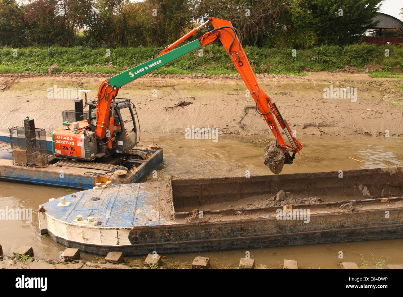 Burrowbridge, Somerset, UK. 30th September, 2014.  Dredging continues along the River Parrett on the Somerset Levels. Today a floating excavator takes river silt from mid channel of the Parrett and offloads it into a barge. The Environment Agency have so far dredged over 6km of river with a target of 8km by the end of October 2014. Stock Photo