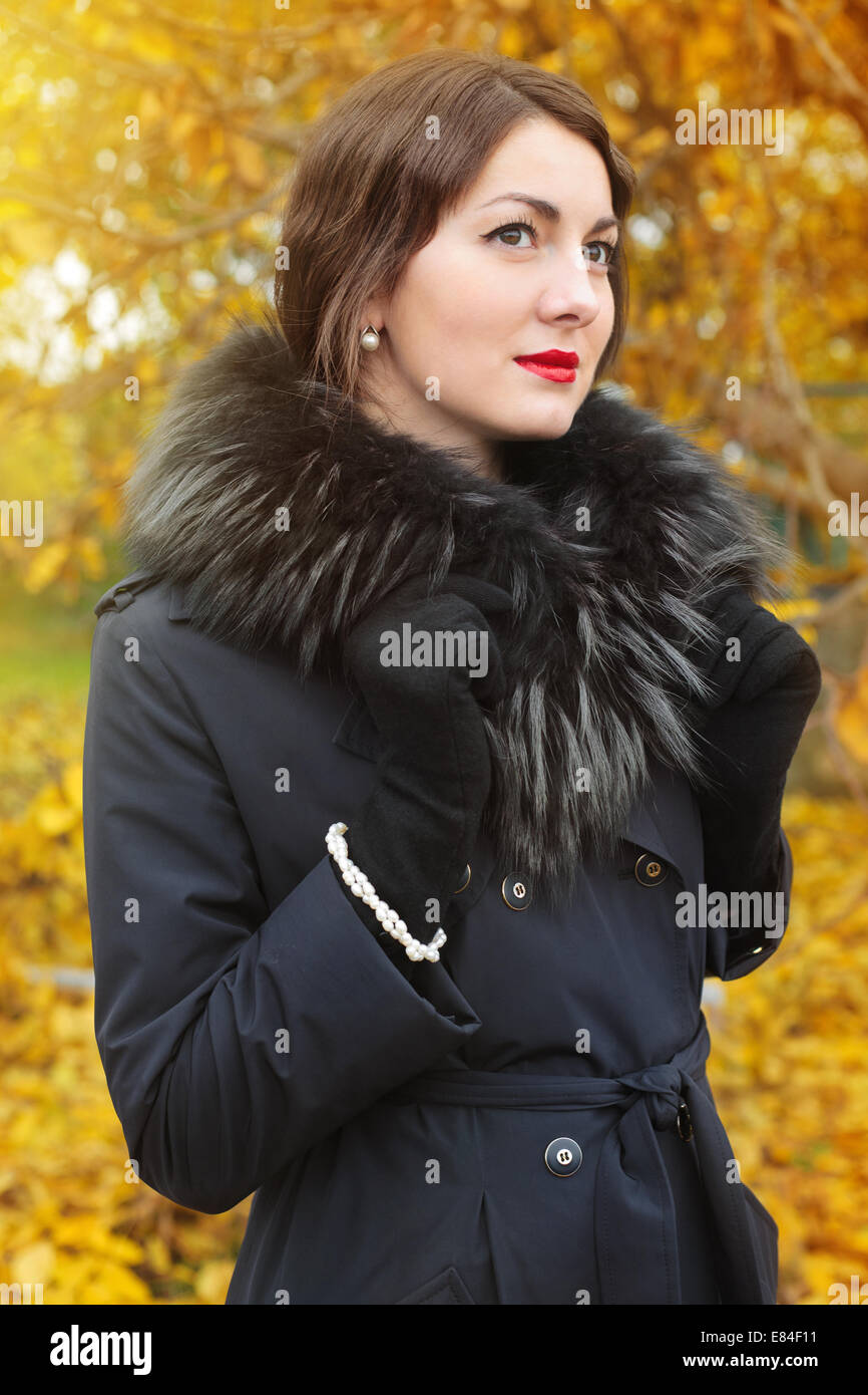 Woman in a black coat on background of autumn tree Stock Photo - Alamy