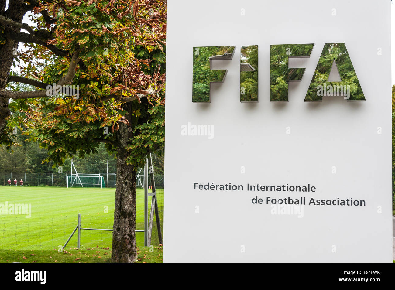 Close up of the sign outside FIFA headquarters in Zurich, with goalposts in background, leaves reflected in the shiny lettering Stock Photo