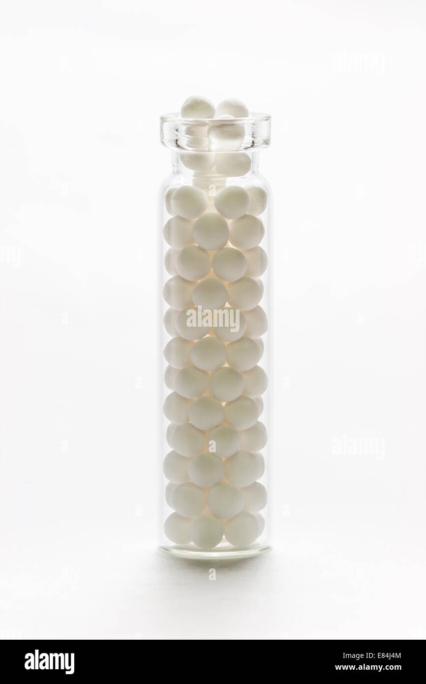 Homeopathic medicinal pills in a bottle backlit on a white background. Stock Photo