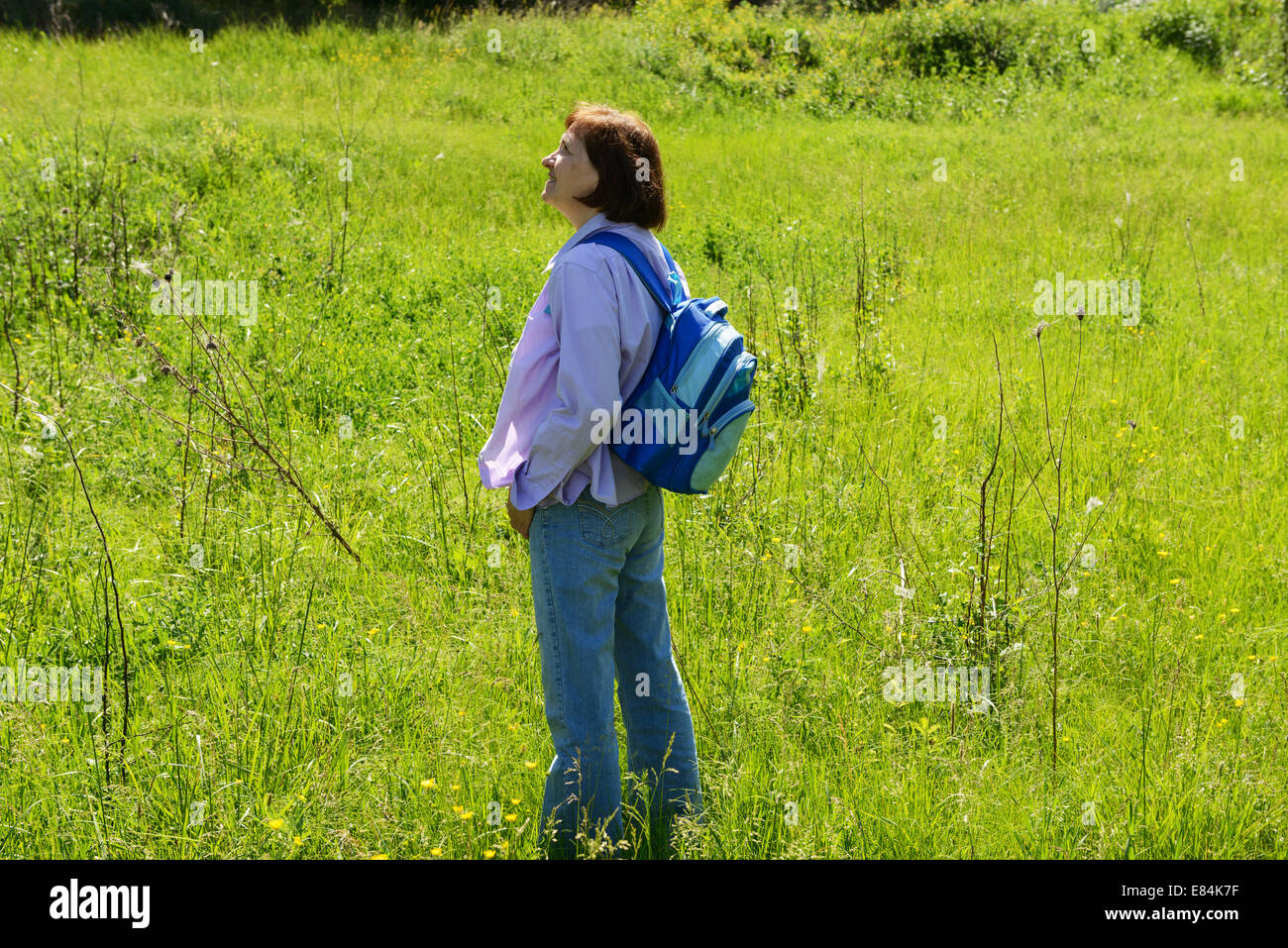 Full length portrait of mature woman in jeans and shirt on bright green ...