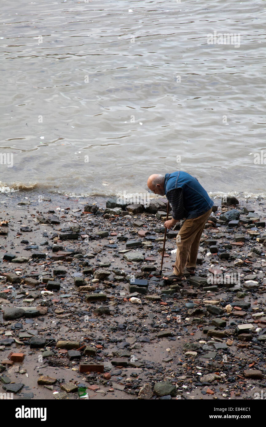 Man Searching the River Thames Shore on Bankside - London UK Stock Photo
