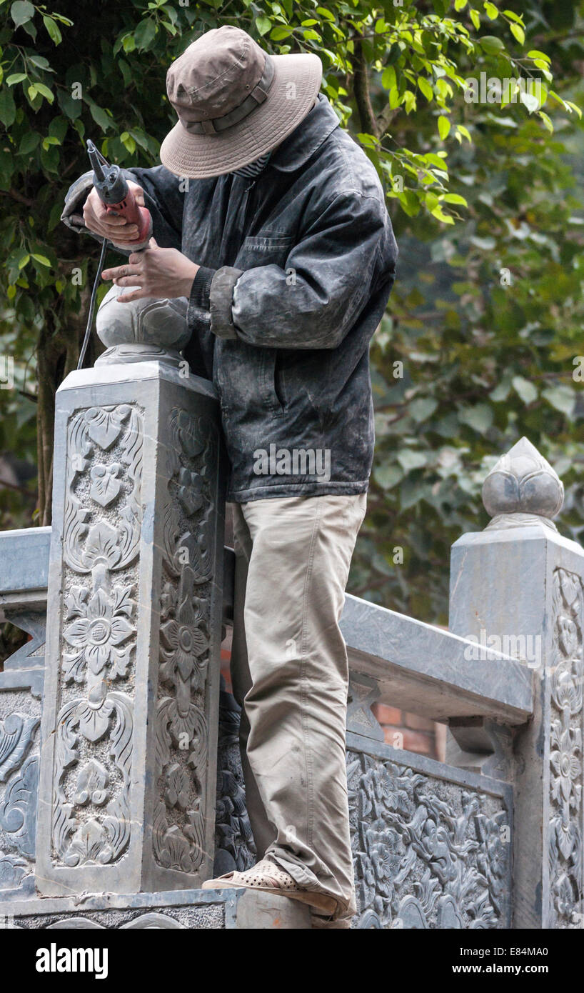 Artist handling electric chisel tool to create flowers in stone Stock