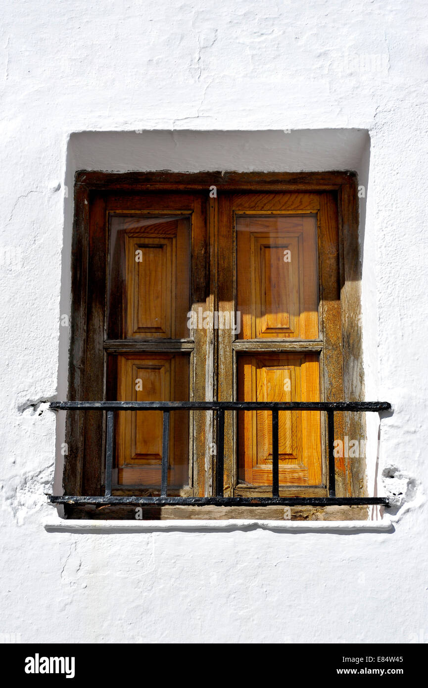 seen from below a whitewashed wall with wooden shuttered window and railing in Spain Stock Photo
