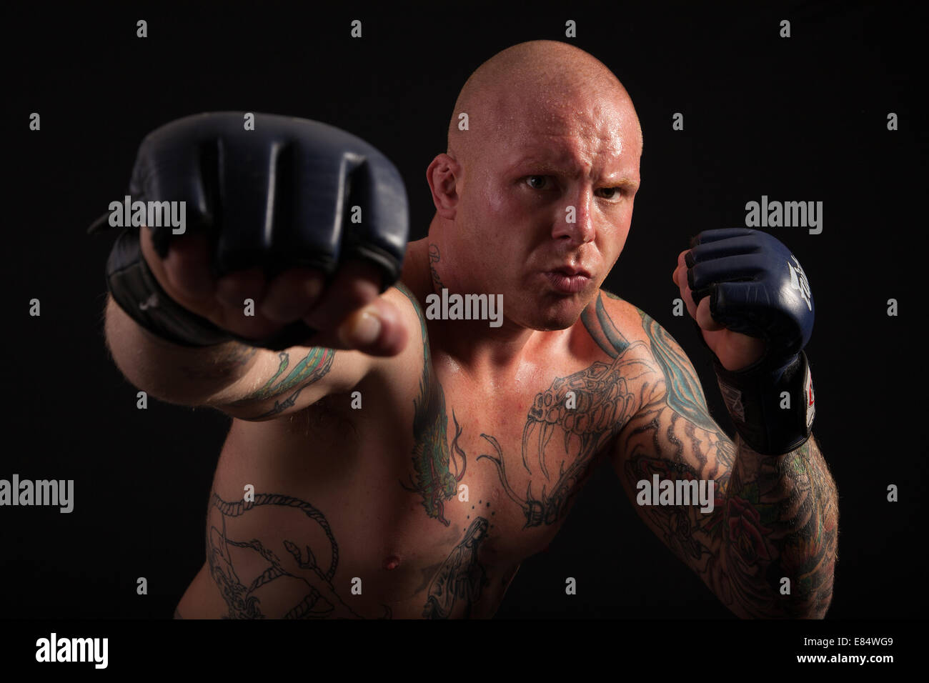 Cage Fighter during work out and warm up. Looking menacingly into camera. Fists in strike pose. Stock Photo