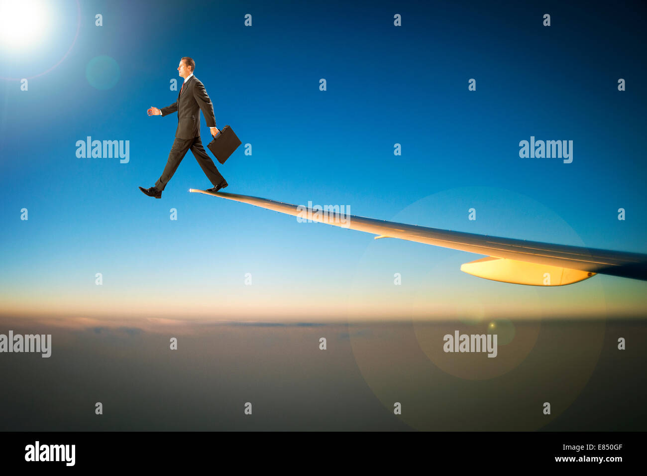 Businessman with briefcase walking off the wing of an airplane Stock Photo