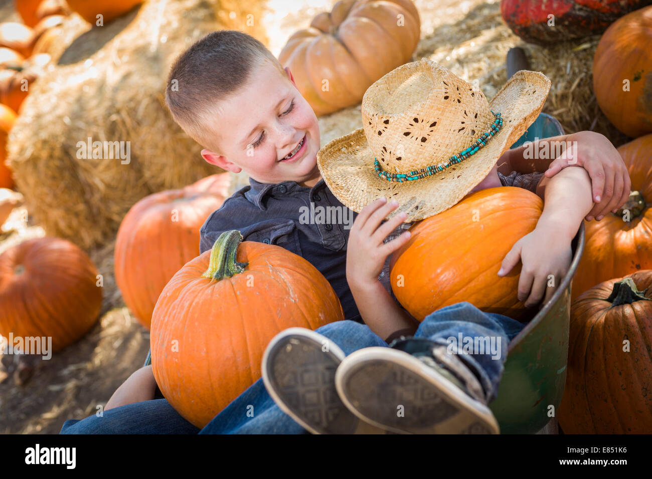 Two Little Boys Playing in Wheelbarrow at the Pumpkin Patch in a Rustic Country Setting. Stock Photo
