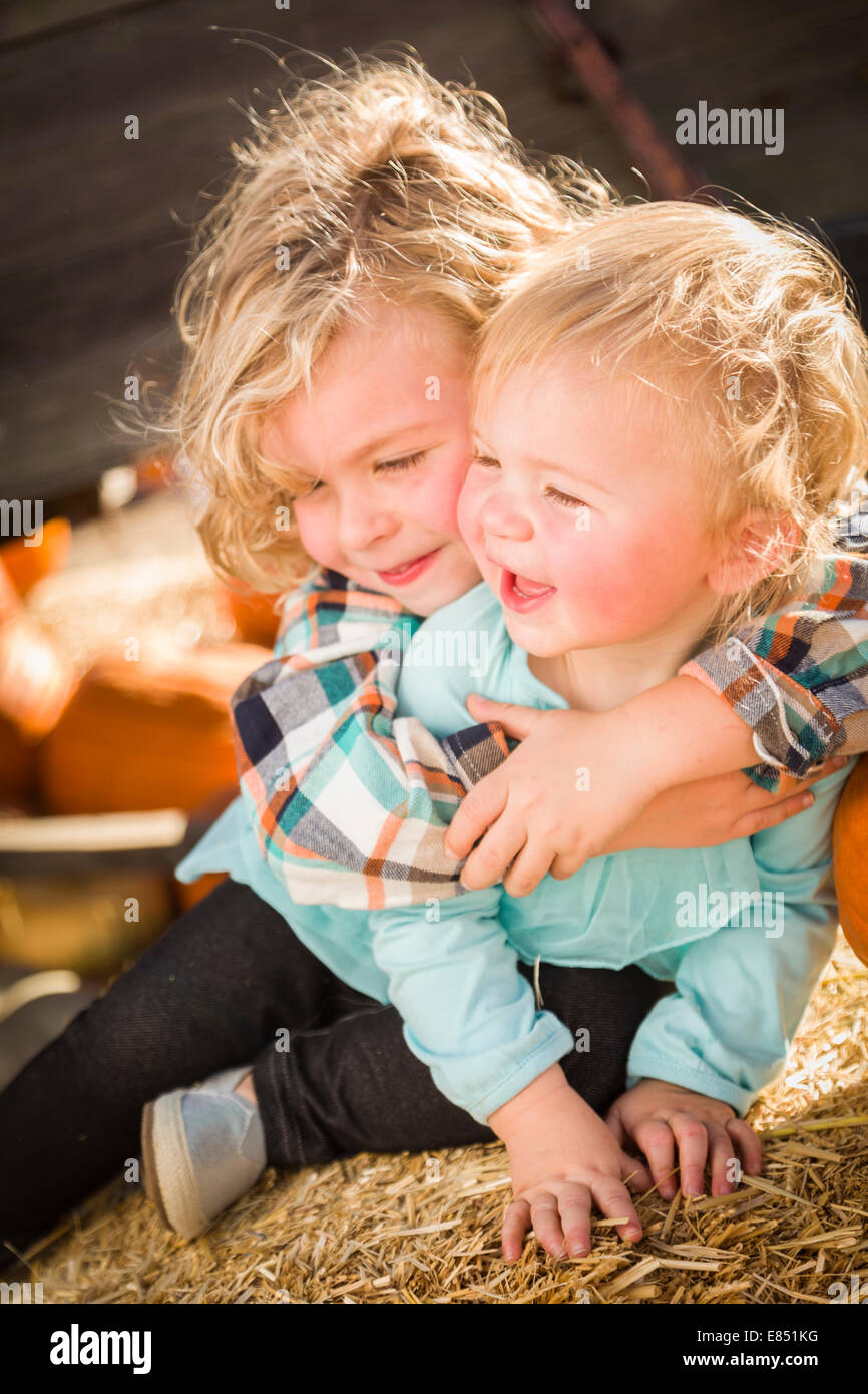 Sweet Little Boy Plays with His Baby Sister in a Rustic Ranch Setting at the Pumpkin Patch. Stock Photo