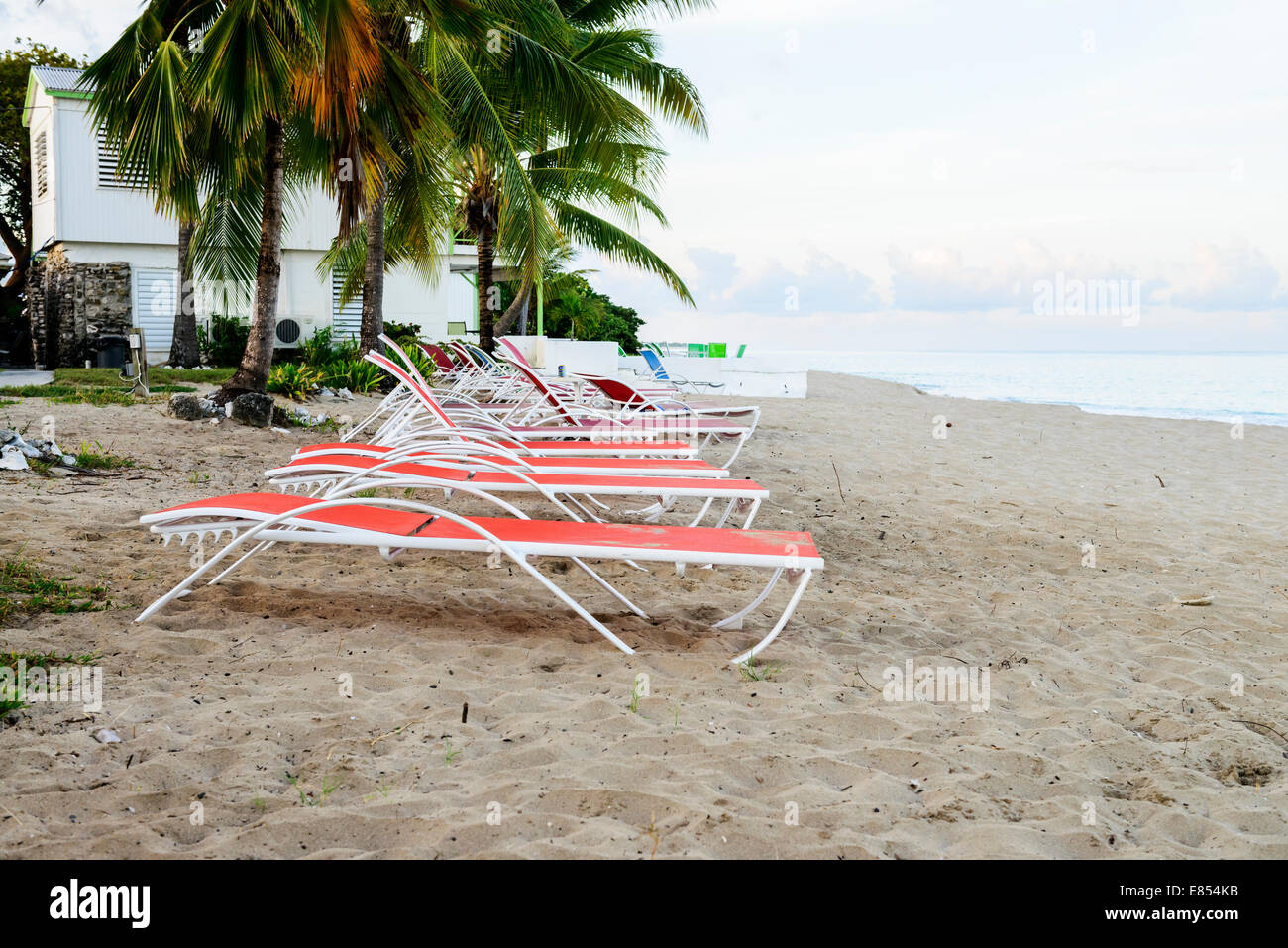 Beach chairs line up on the beach, west end, of St. Croix, U.S. Virgin Islands at dawn. Cottages by the Sea resort. Stock Photo