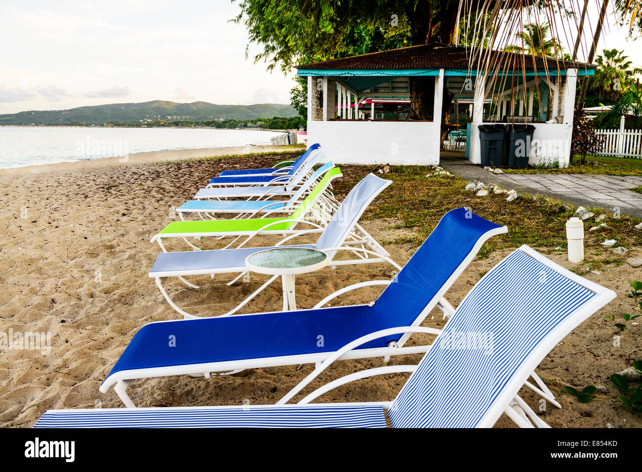 Beach chairs line up on the beach, west end of St. Croix, U.S. Virgin Islands at dawn. Cottages by the Sea resort. Stock Photo