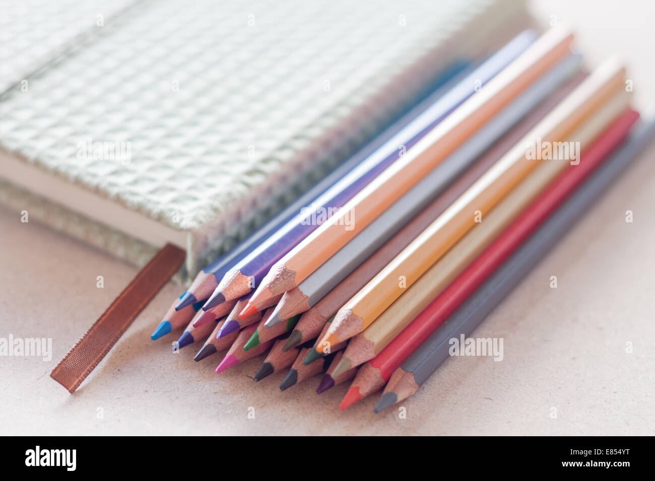 Cluster of colorful pencil crayons with green notebook, stock photo Stock Photo