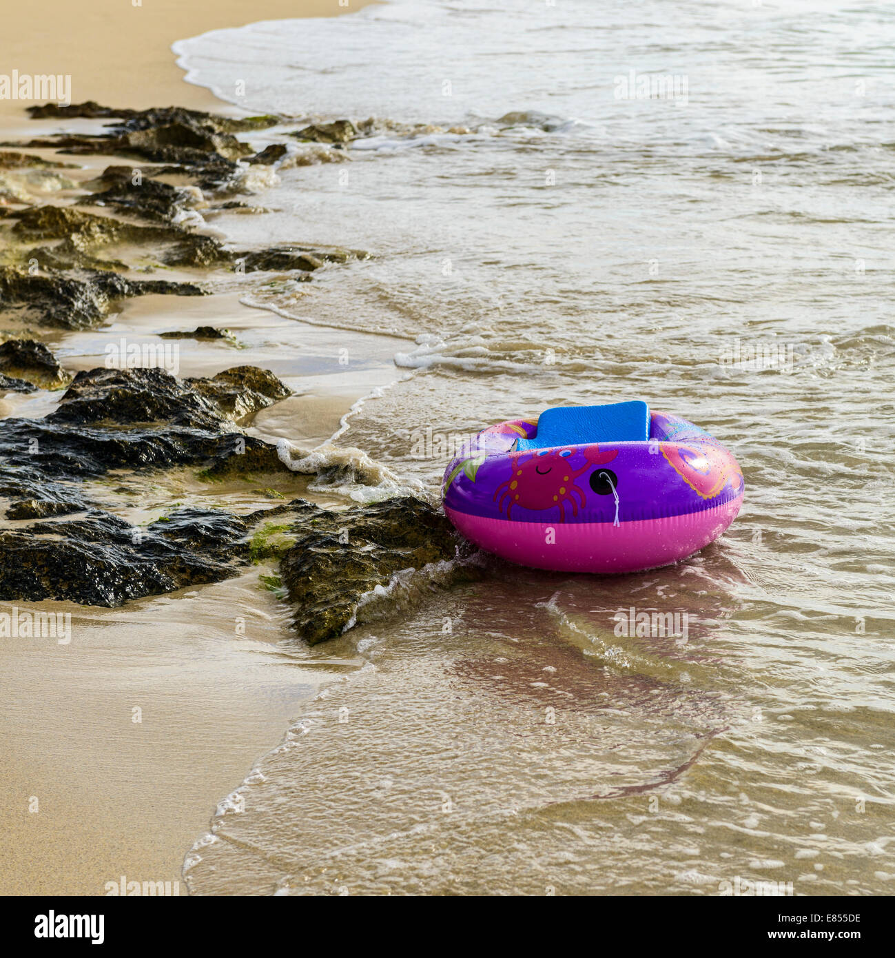 A child's inflatable plastic boat floats free on a tropical beach in St