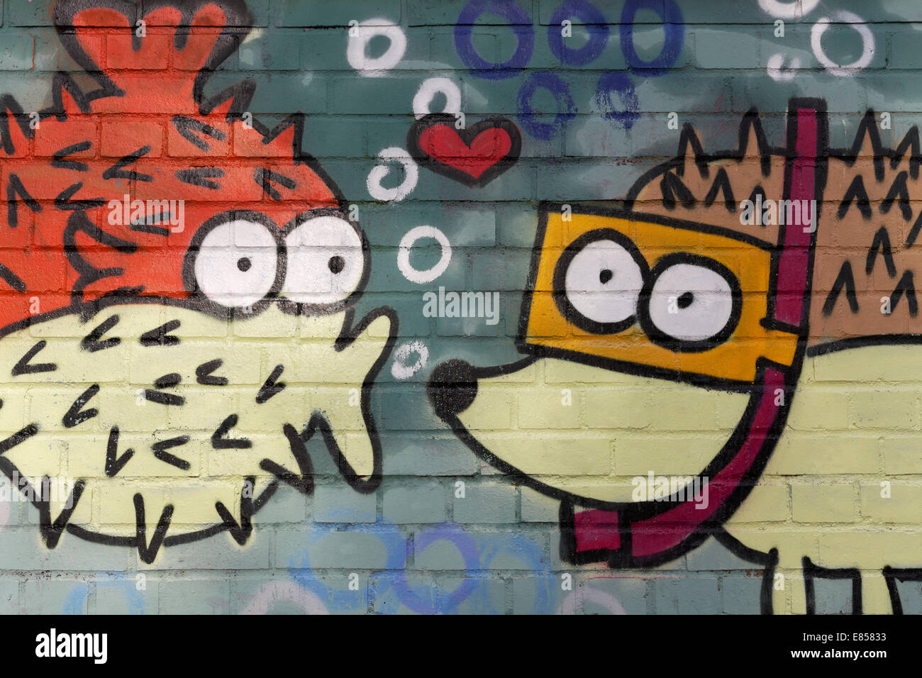 Spiny fish figure kissing a hedgehog figure wearing goggles, mural, North Rhine-Westphalia, Germany Stock Photo