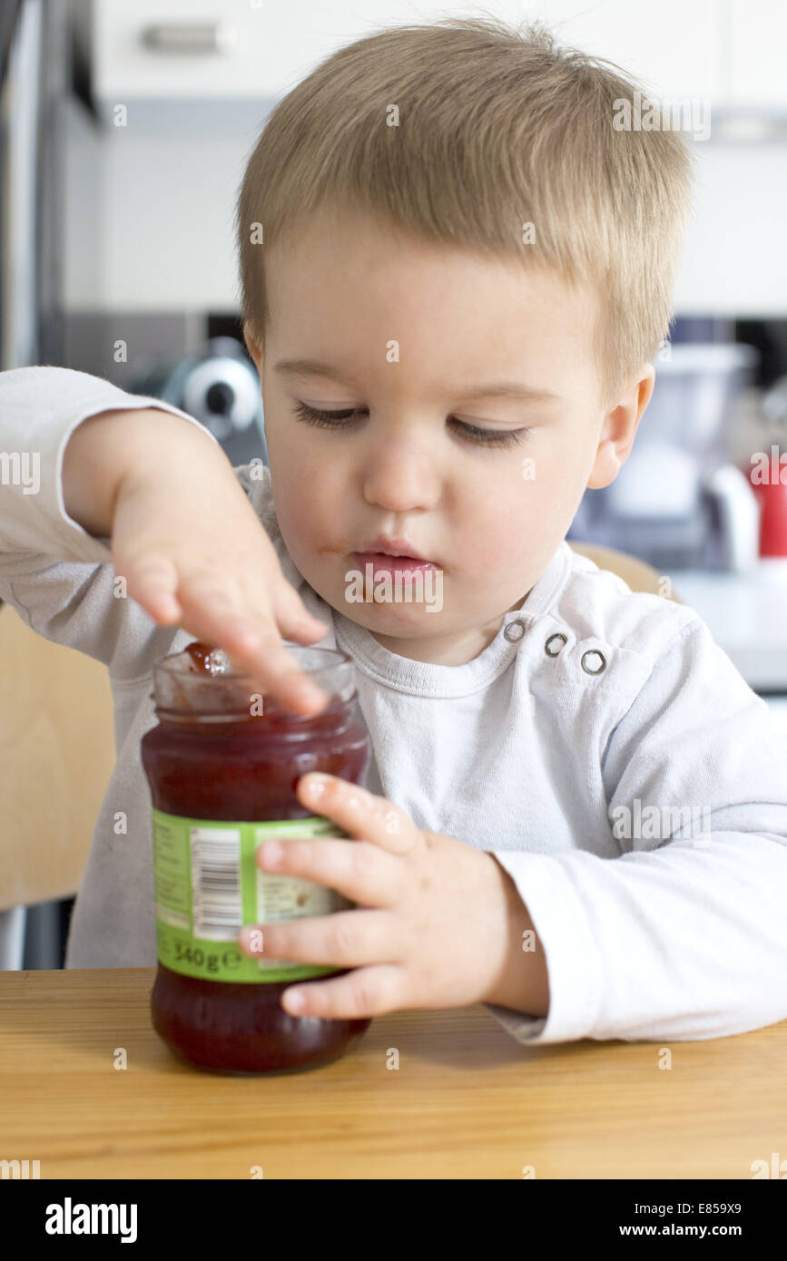 Toddler boy eating jam from jar with his finger Stock Photo Alamy
