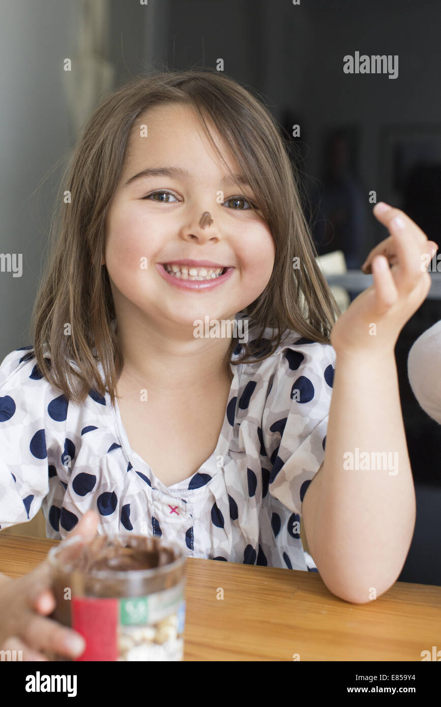 Little girl eating chocolate sauce from a jar with her fingers Stock Photo