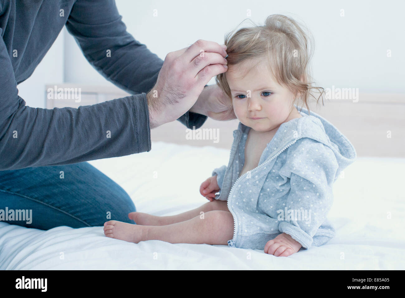 Father fixing baby girl's hair, cropped Stock Photo