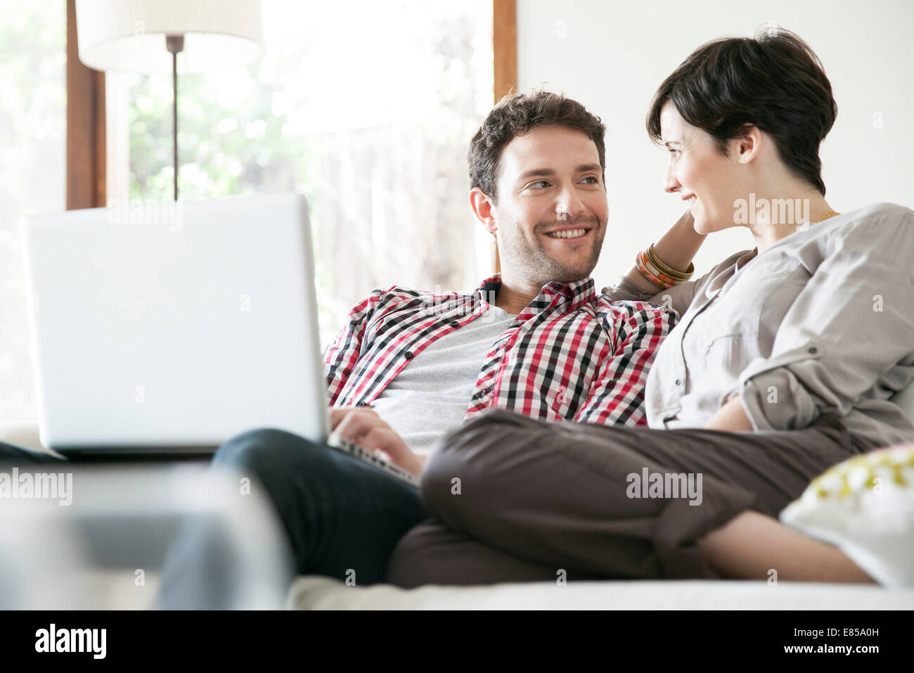 Couple relaxing together on sofa with laptop computer Stock Photo - Alamy
