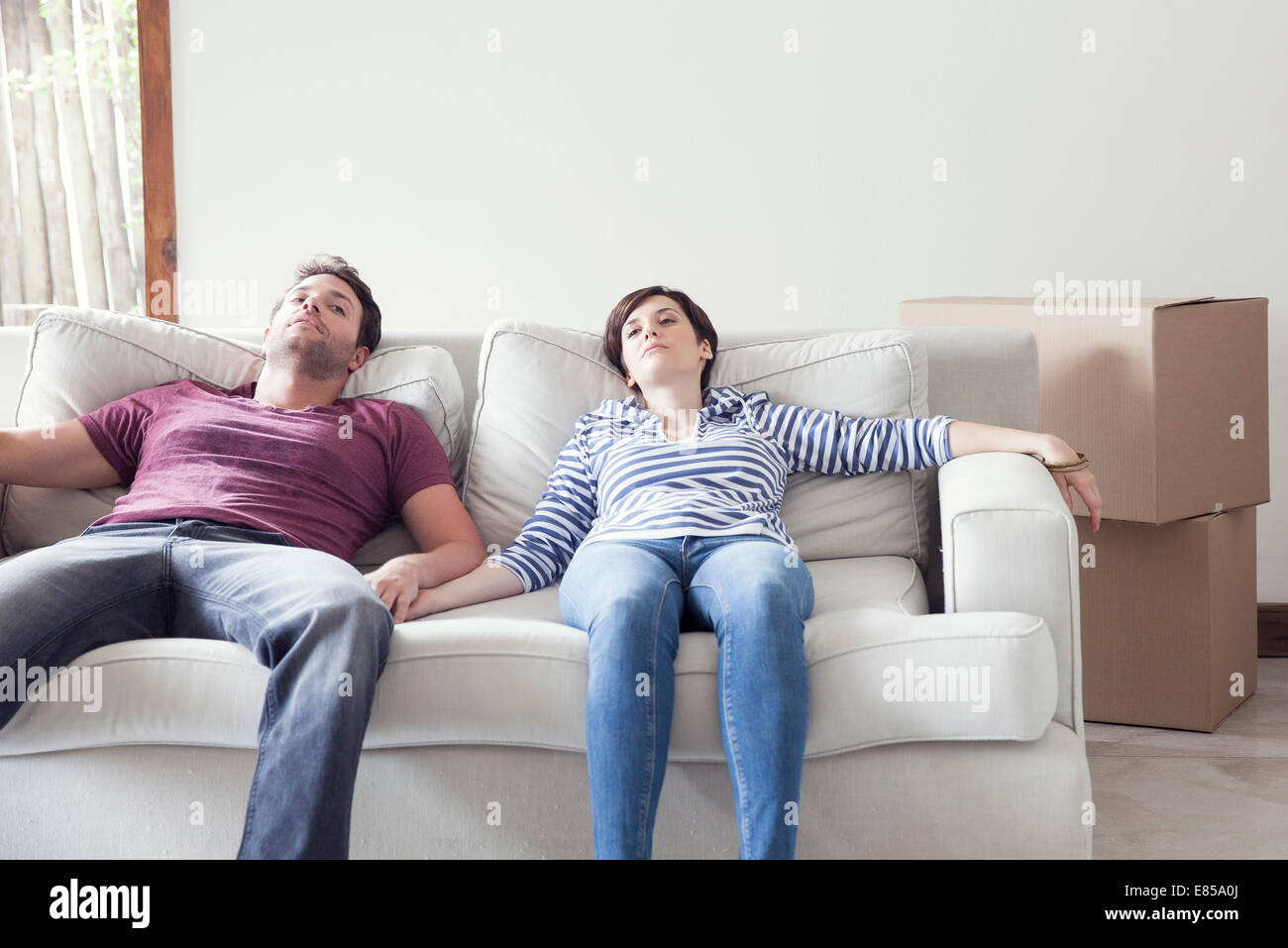Couple relaxing on sofa while moving house Stock Photo - Alamy