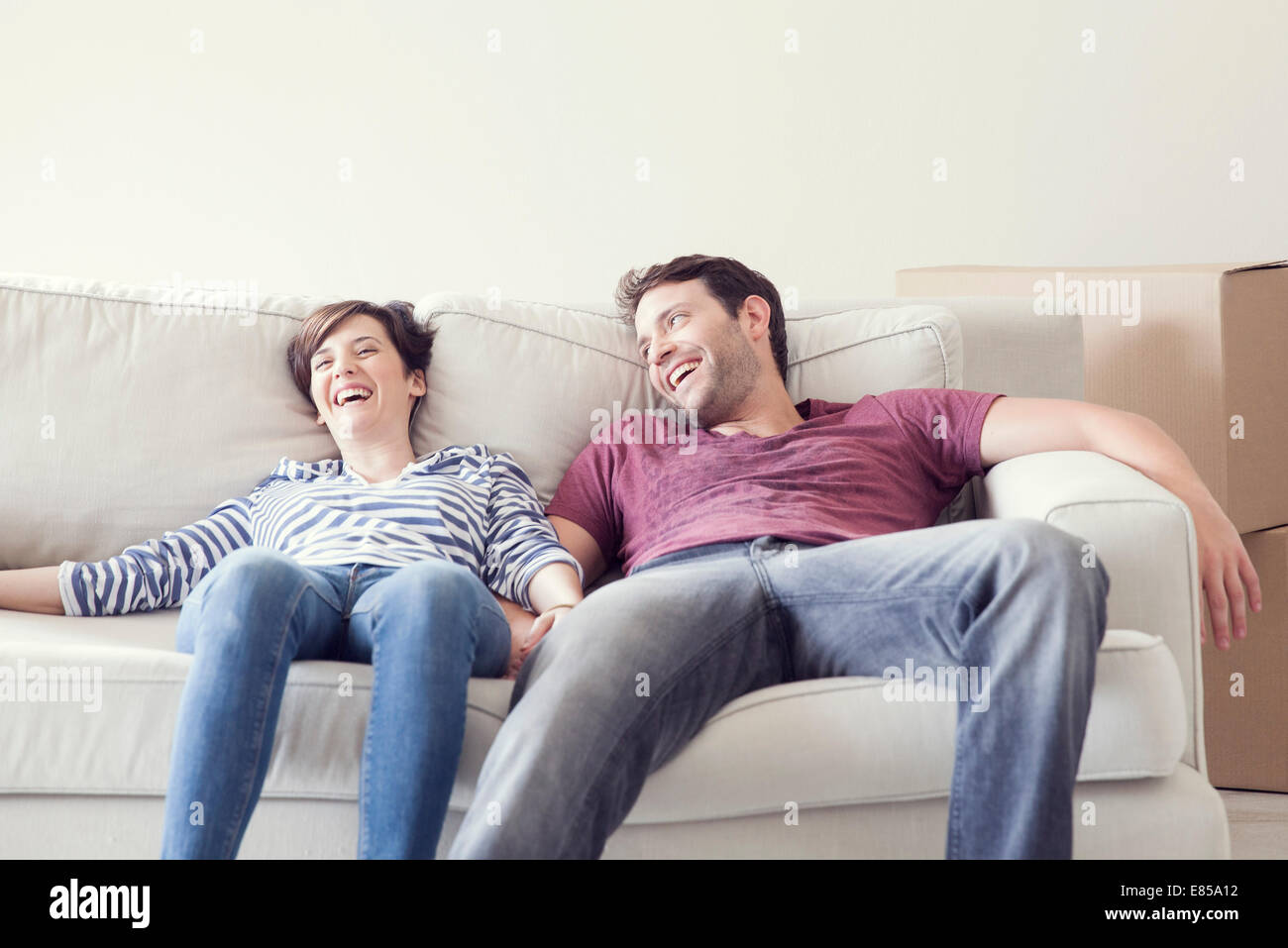 Couple relaxing on sofa while moving house Stock Photo - Alamy