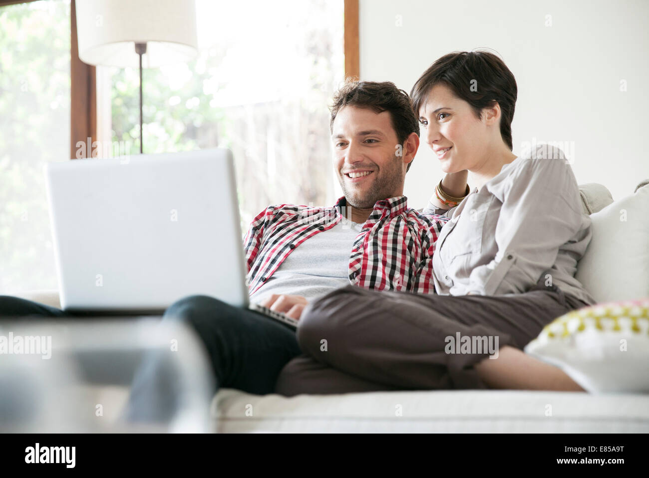 Couple relaxing together on sofa with laptop computer Stock Photo - Alamy
