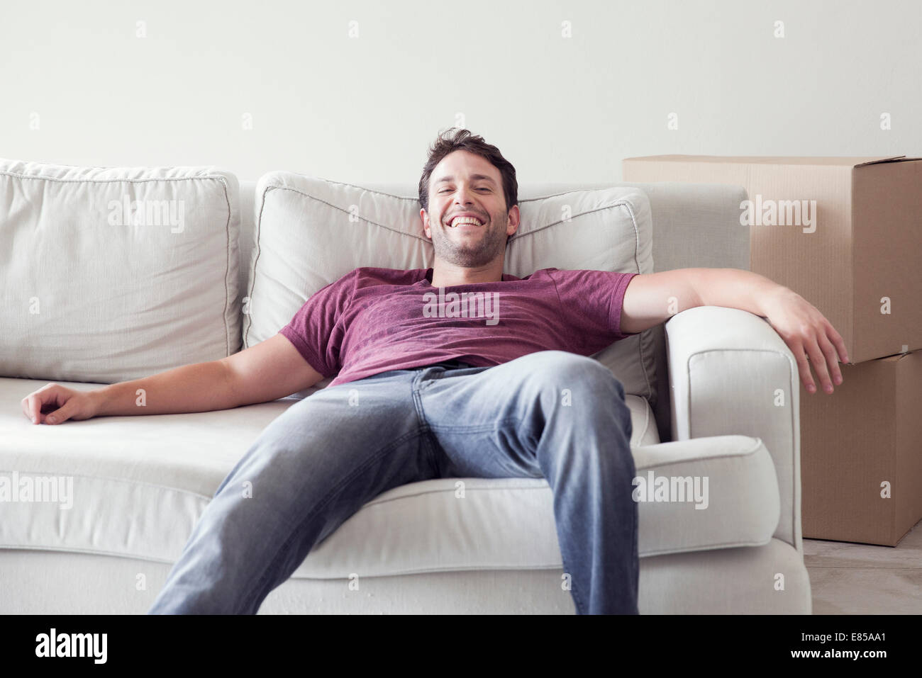 Man relaxing on sofa while moving house Stock Photo - Alamy