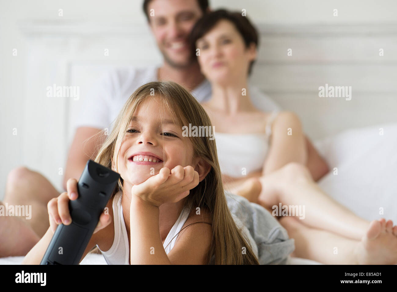 Little girl watching tv in bedroom with parents Stock Photo
