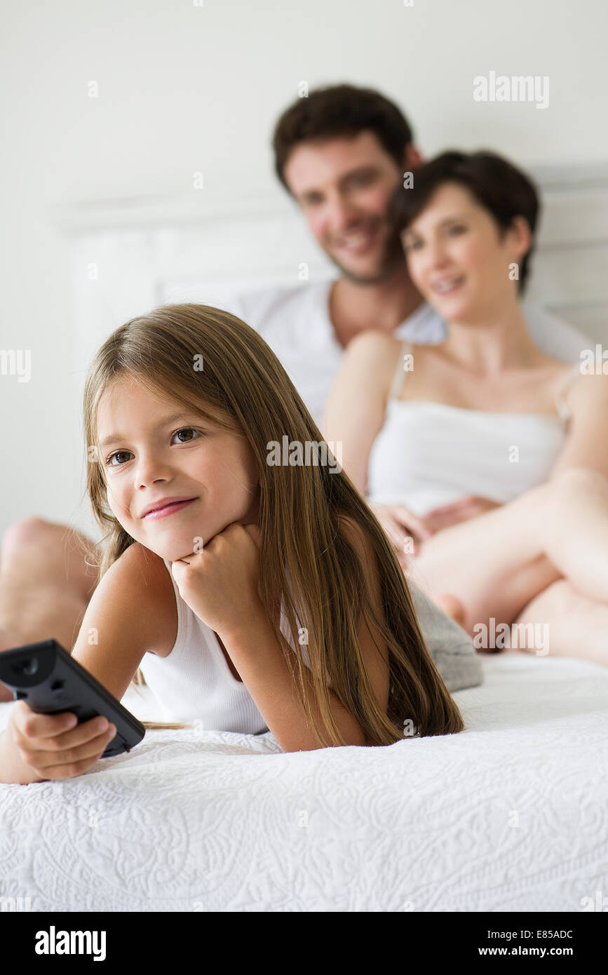 Little girl watching tv in bedroom with parents Stock Photo