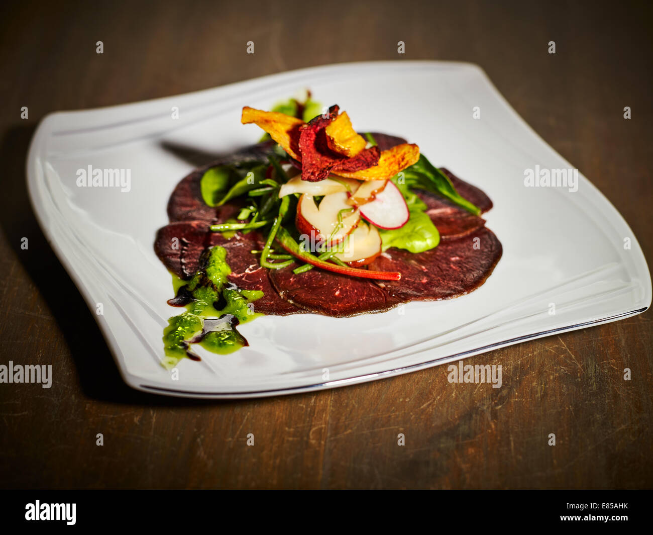 The appetizer, cold-smoked reindeer meat and the salad on the plate Stock Photo