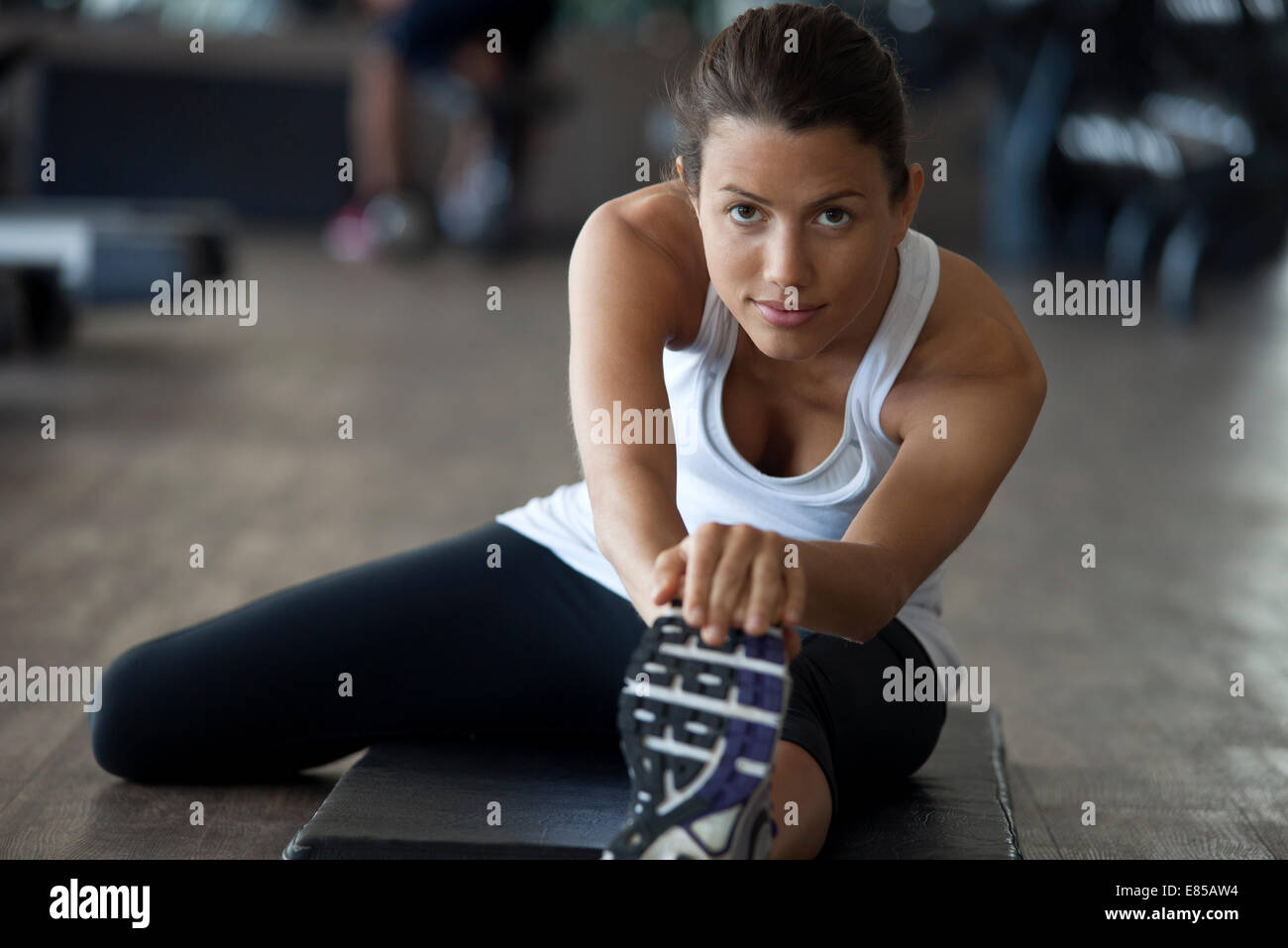 Woman at gym warming up with leg stretches Stock Photo