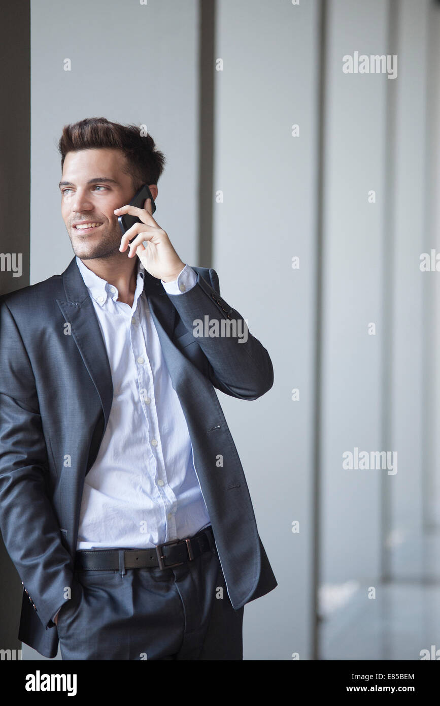 Young man leaning against buiding column talking on cell phone Stock Photo