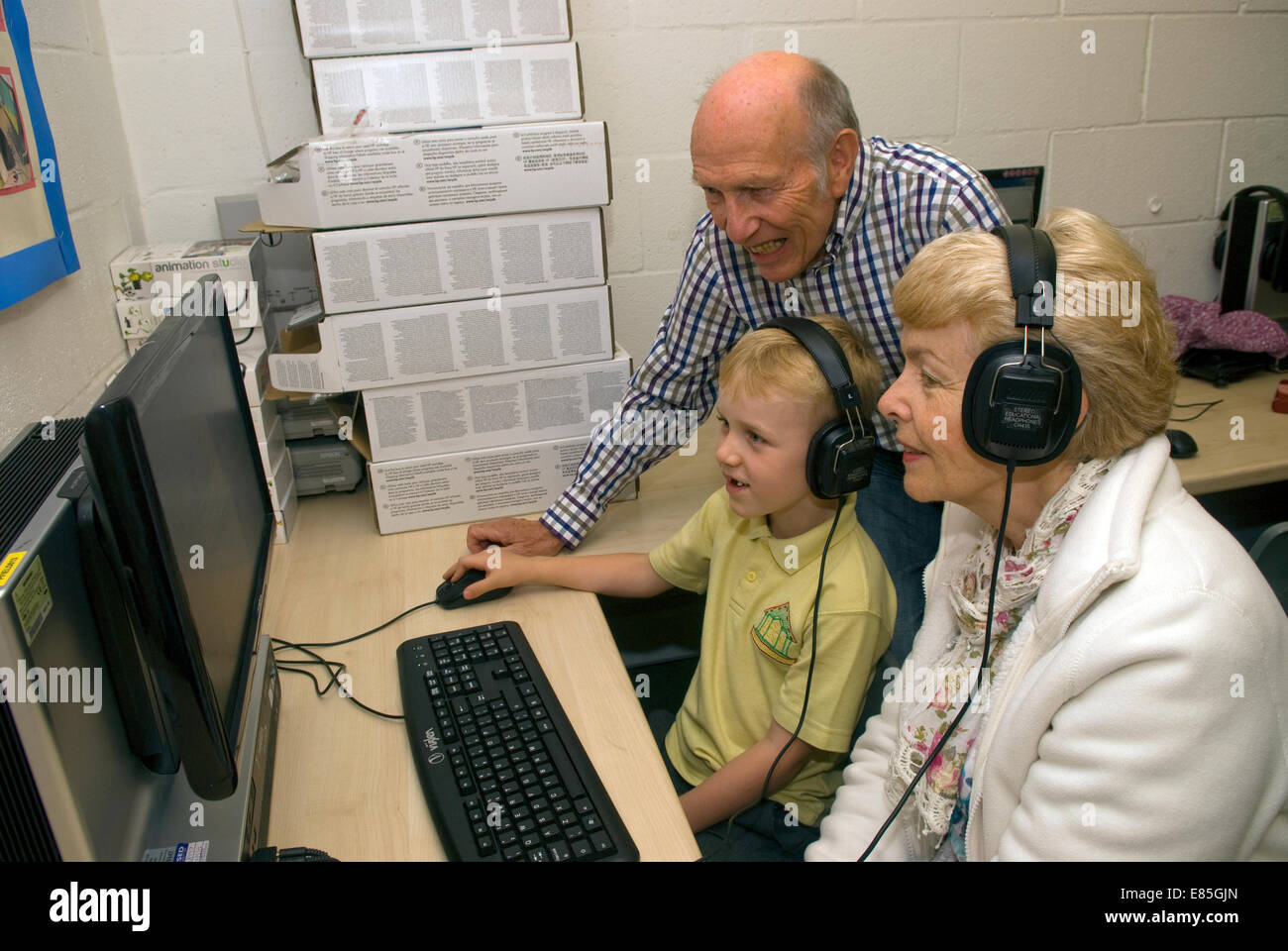 Silver surfers receiving assistance from a primary school pupil in computer skills, Petersfield, Hampshire, UK. Stock Photo