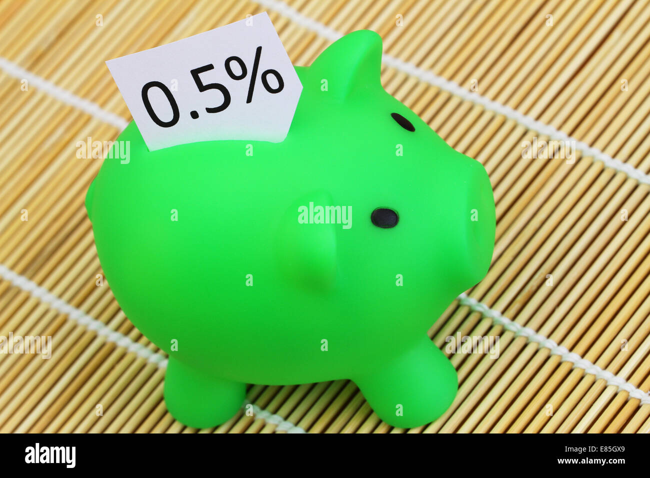 Piggy bank with note showing 0,5% interest rate sticking out of it Stock Photo