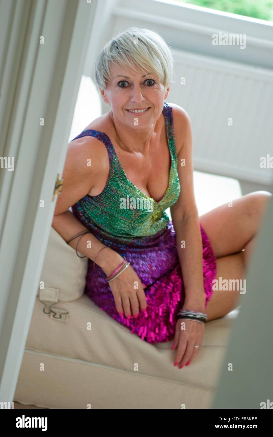 Mature woman sits in short evening dress Stock Photo - Alamy