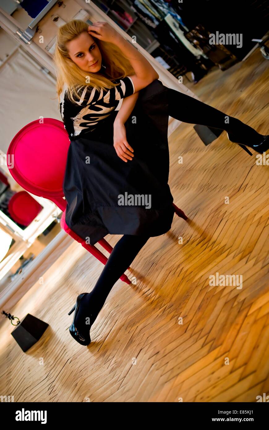 Blonde woman sits posing on chair Stock Photo - Alamy