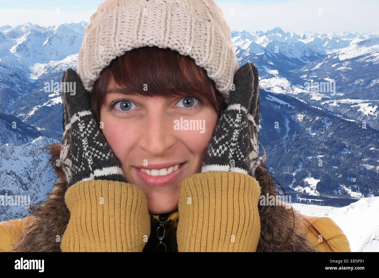 Portrait of a young woman freezing in the cold in winter with gloves and cap in the mountains Stock Photo
